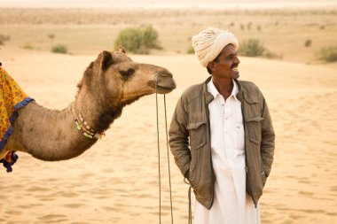 JAISALMER, INDIA - 23 Aralık 2015: Rajasthani adam ve devesi Jaisalmer, Hindistan 'da Thar çölünde