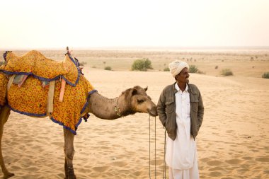 JAISALMER, INDIA - 23 Aralık 2015: Rajasthani adam ve devesi Jaisalmer, Hindistan 'da Thar çölünde
