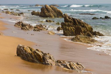 Kumlu deniz sahilindeki kayaların manzarası. 