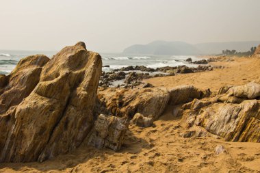 Kumlu deniz sahilindeki kayaların manzarası. 