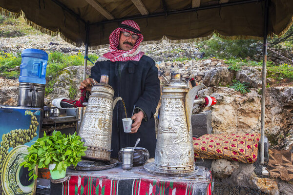 AJLOUN, JORDAN - March 2019: Bedouin man traditionally dressed preparing Bedouin mint tea in Ajloun, Jordan