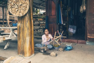 Luang Prabang, Laos - Nisan 2019: Luang Prabang, Laos'ta dokuma makinesinde çalışan Lao kadını