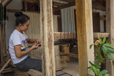 Luang Prabang, Laos - Nisan 2019: Luang Prabang, Laos'ta dokuma makinesinde çalışan Lao kadını