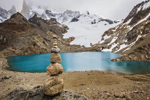 Stone pyramid in front of turquoise water lake in Patagonia, Los Glaciers National park. Beautiful view of Laguna De Los Tres, Monte Fitz Roy, Torre y Poincenot, El Chalten, Patagonia, Argentina