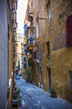 Geleneksel Malta mimarisi. La Valetta 'nın eski tarihi parçası. Dışarıda insanlar ve dar sokaklar, Malta.