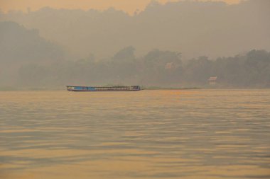 Luang Prabang, Laos - Nisan 2019: Gün batımında Mekong nehri üzerinde uzun tekne, Luang Prabang, Laos