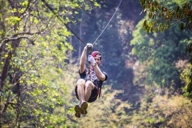 LAOS - April 2019: Man in the jungle on zip line. Ziplining in Laos jungle, Gibbon Experience adventure tour, Laos