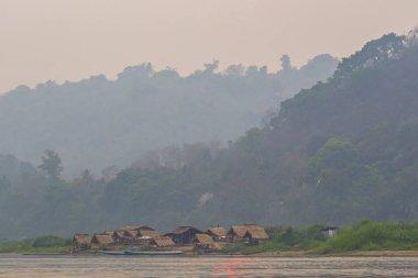 Luang Prabang, Laos - Nisan 2019: Sahilde küçük köy evleri ile Mekong nehri üzerinde güzel gün batımı, Luang Prabang, Laos