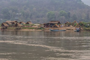 Luang Prabang, Laos - Nisan 2019: Sahilde küçük köy evleri ile Mekong nehri üzerinde güzel gün batımı, Luang Prabang, Laos