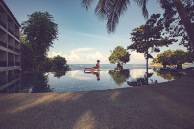 Koh Tao, Tayland - Nisan 2019: Yüzme havuzuyakınında yoga yapan kadın. Savaşçı yoga denize karşı poz, Koh Tao, Tayland