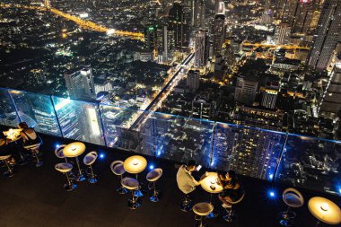 Bangkok, Tayland - Nisan 2019: Bangkok, Tayland 'daki King Power Mahanakhon gökdeleninin tepesindeki açık hava restoranında gece manzarası