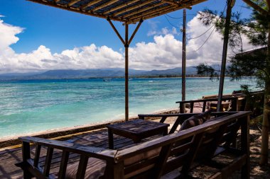 Gili Air, Bali, Endonezya 'da ahşap mobilyaları ve şemsiyeleri olan rahat bir plaj salonu.
