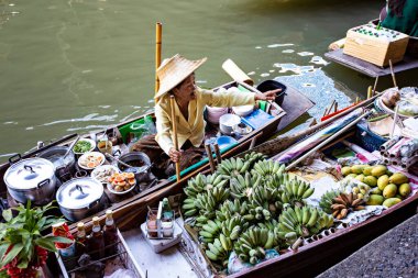 İnsanlar Bangkok, Tayland 'a yakın Damnoen Saduak Yüzen Pazarı' nda sebze ve yiyecek satıyor.