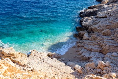 Parlak turkuaz suyu ve kayaları olan deniz kıyısı.