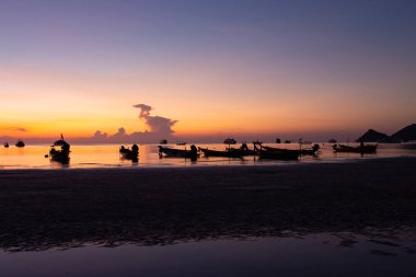 Gün batımında, akşam deniz kıyısında demirli tekneler.