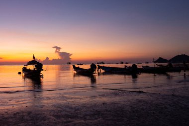 Gün batımında, akşam deniz kıyısında demirli tekneler.