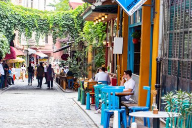 Dışarıda masaları olan rahat bir sokak kafesi, eski İstanbul 'un Balat bölgesinde oturan ve konuşan insanlar.