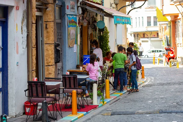 Dışarıda masaları olan rahat bir sokak kafesi, eski İstanbul 'un Balat bölgesinde oturan ve konuşan insanlar.