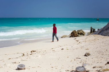 Zanzibar 'da güzel bir sahil. Kendwa köyü, Zanzibar, Tanzanya 'da mavi suyu olan cennet plajı. Sahilde yürüyen Afrikalı adam, Zanzibar.