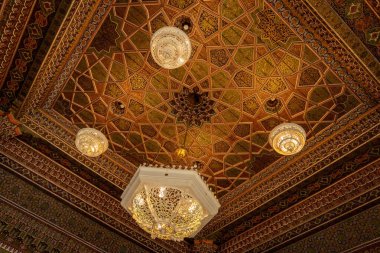 TASHKENT, UZBEKISTAN - 7 Eylül 2025: Taşkent Özbekistan 'daki Uygulamalı Sanatlar Müzesinde avizelerle oyulmuş geleneksel ahşap ve mozaik tavan