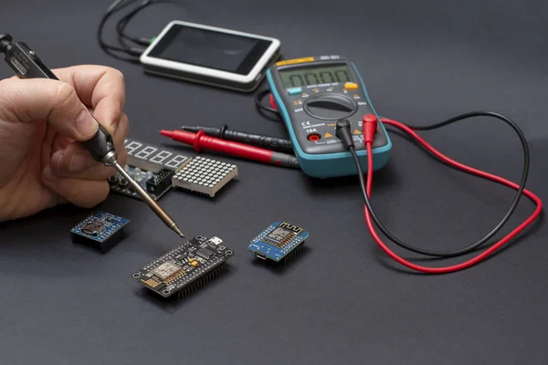 Soldering electronics on black background - wifi modules, displays, multimeter and osciloscope