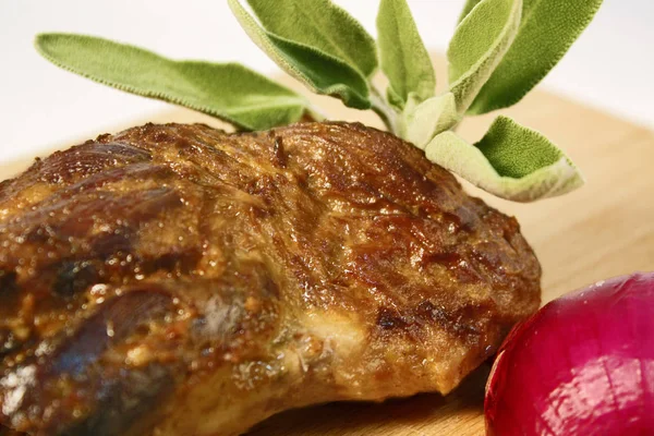 Piernas de cordero asadas cocinadas lentamente exhibidas en tabla de cortar de madera con cebolla roja y hojas de menta fresca . —  Fotos de Stock