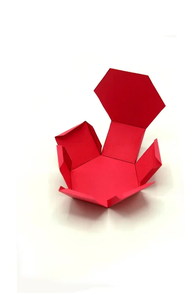 Geometric shape cut out of red paper and photographed on white background.Hexagonal prism. 2D shapefoldable to form a 3-dimensional shape or a solid.