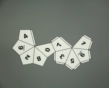 Geometrik şekil kağıttan kesilmiş ve gri arka plan üzerinde yukarıdan fotoğraflandı. Decahedron'un geometri ağı. 3 boyutlu bir şekil veya katı bir şekil oluşturmak için katlanabilir 2 boyutlu şekil.