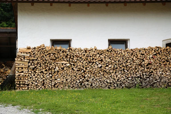 Ułożone Drewno kominkowe w pobliżu białej ściany rustykalnego domu. — Zdjęcie stockowe