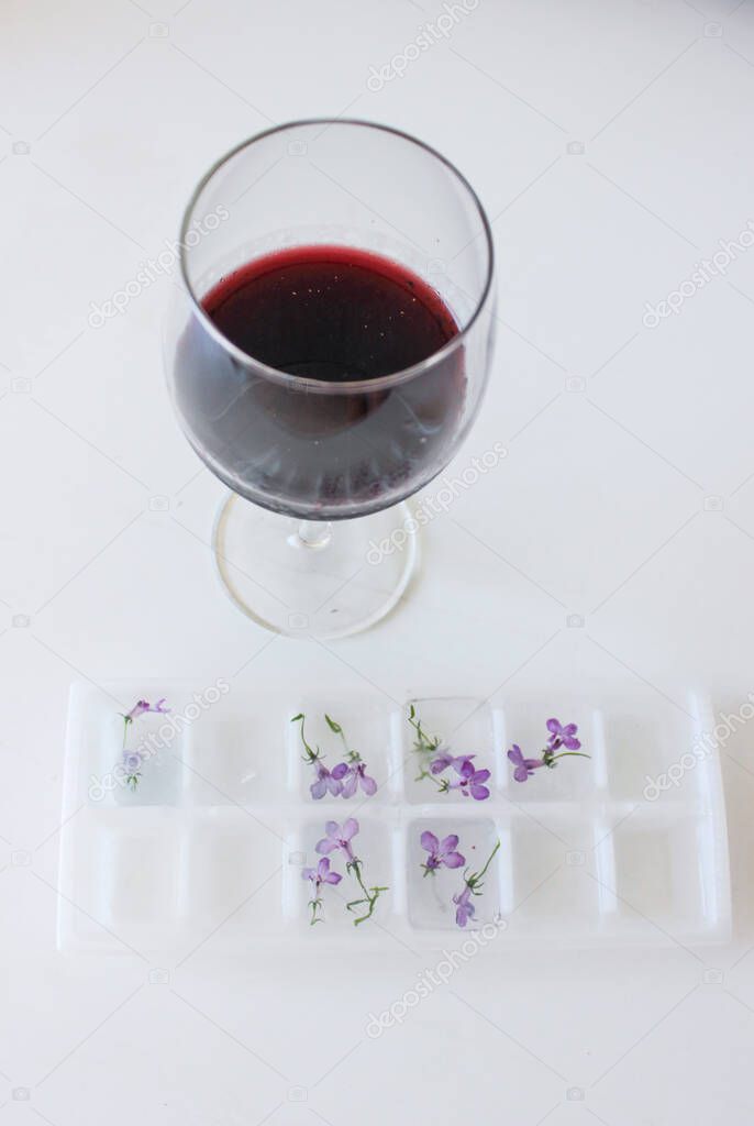 A glass of red wine and ice with natural flowers