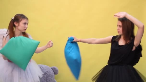 Två vänner har roligt kämpar kuddar i form av en ängel och en demon — Stockvideo