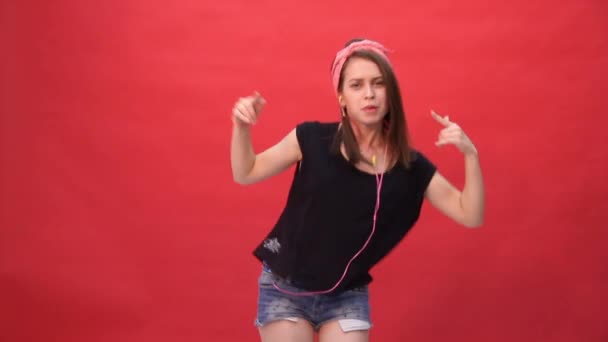 Chica bailando y divirtiéndose sobre un fondo rojo — Vídeo de stock