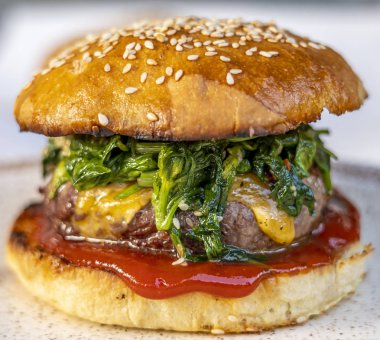 sığır köftesi ile cheeseburger, ıspanak, kırmızı sos, çedar peyniri