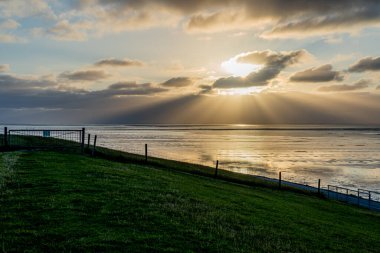 Kuzey Denizi 'nin çorak sularında gün batımında Bernersiel, Almanya yakınlarında