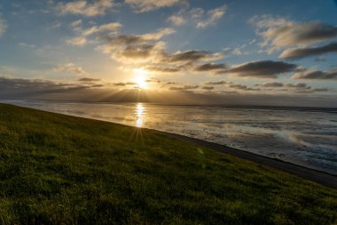 Kuzey Denizi 'nin çorak sularında gün batımında Bernersiel, Almanya yakınlarında