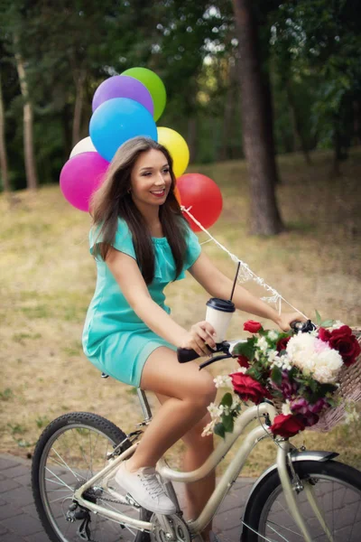 beautiful fashion girl with bicycle and balloons and coffe