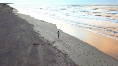 Hava dron genç çekici adam sahilde güneş doğarken koşu ile kaydırma. Egzersiz uygulama çalışan fitness ve sağlıklı yaşam konsepti.