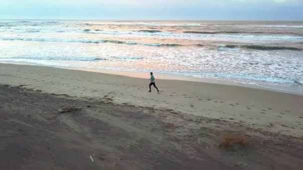 Panorámica Aérea Con Dron Joven Atractivo Trotando Playa Amanecer Ejecutar — Vídeos de Stock