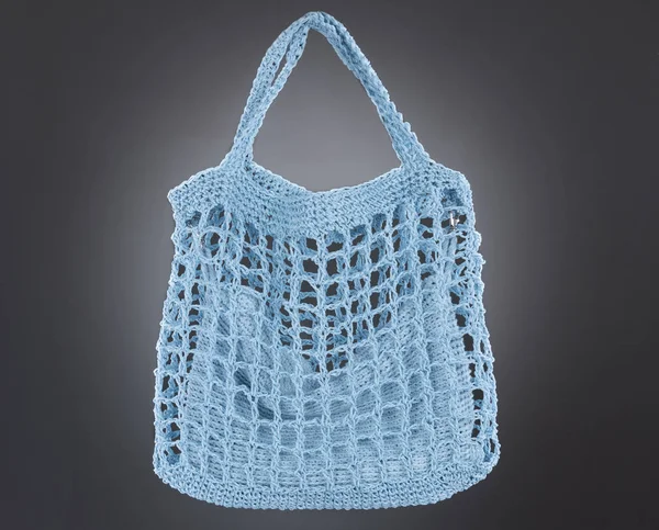 Handmade sky blue string bag on a gray background. Close-up.