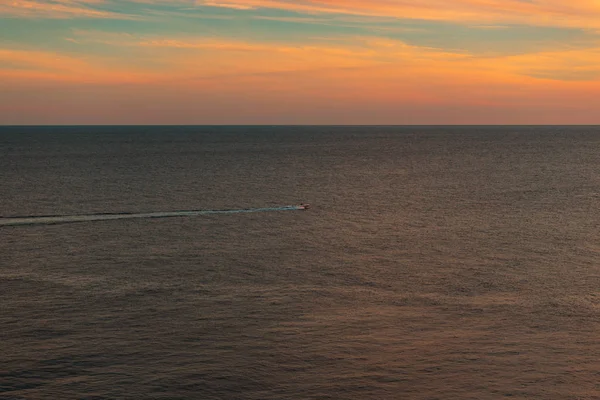 Pink sunset at the sea. The boat is sailing