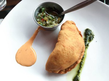 Chimichurri soslu beyaz bir tabakta börek.