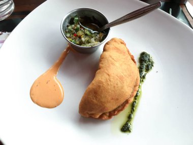 Chimichurri soslu beyaz bir tabakta börek.