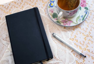 Çay fincanı ve dantel masa örtüsü sahnesi.