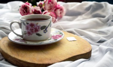 Yatakta çay, dinlenmek için hazır. Arka tarafta şakayıklar var.