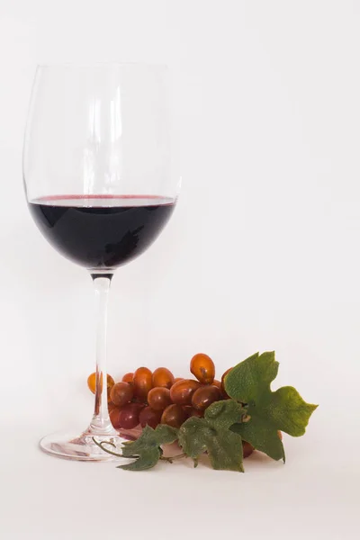 Glas Rotwein mit einer Traube — Stockfoto