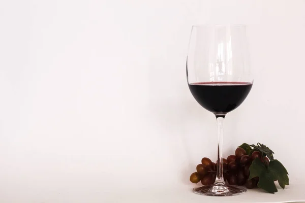 Verre de vin rouge avec un bouquet de raisins — Photo