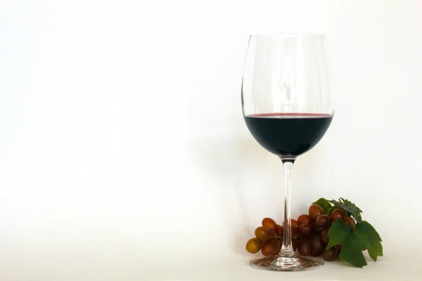 Verre de vin rouge avec un bouquet de raisins — Photo