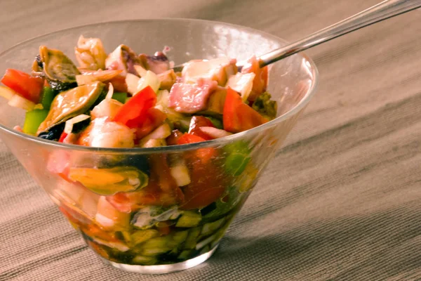 Şeffaf kâse kabuklu deniz ürünleri, sebze salata ve masa örtüsünün üzerinde çatal.