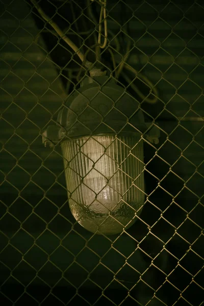 Old industrial lamp behind the net fence.