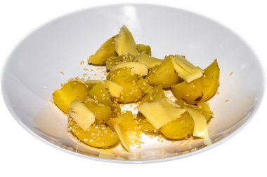 Beyaz bir tabakta peynir ve susam ile haşlanmış patates.